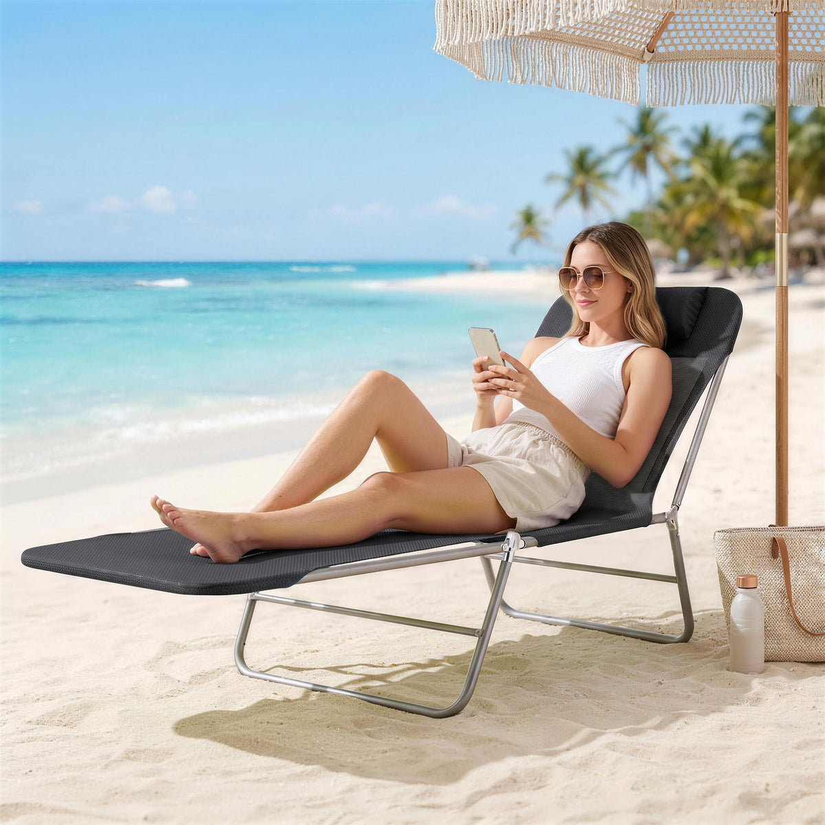 Black reclining sun lounger with a padded headrest and silver folding frame