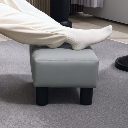 Grey padded footstool supporting a person's feet