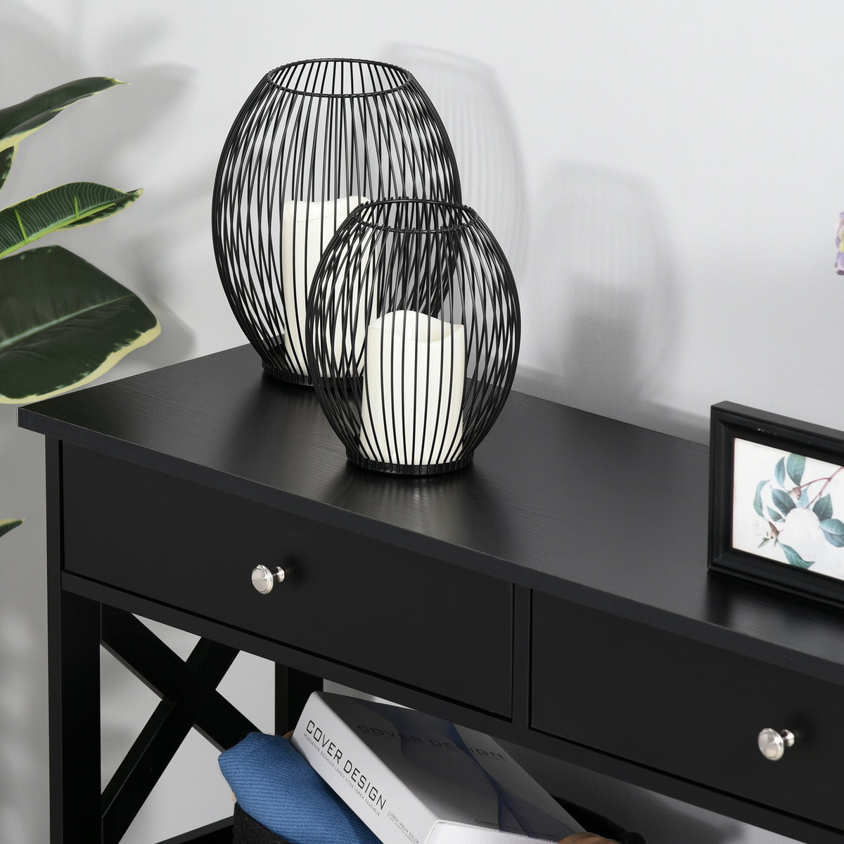 Close-up of black console table with silver drawer knobs and X-frame supports.