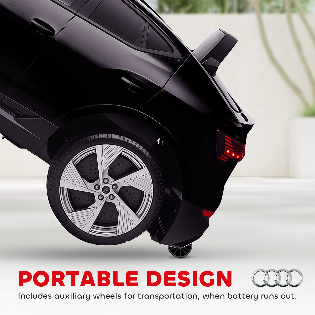 Black Audi e-tron ride-on car rear wheel and auxiliary transport wheels close-up.