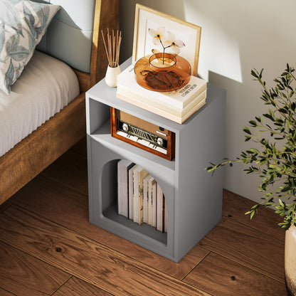 Grey bedside table with two open compartments, shown beside a bed