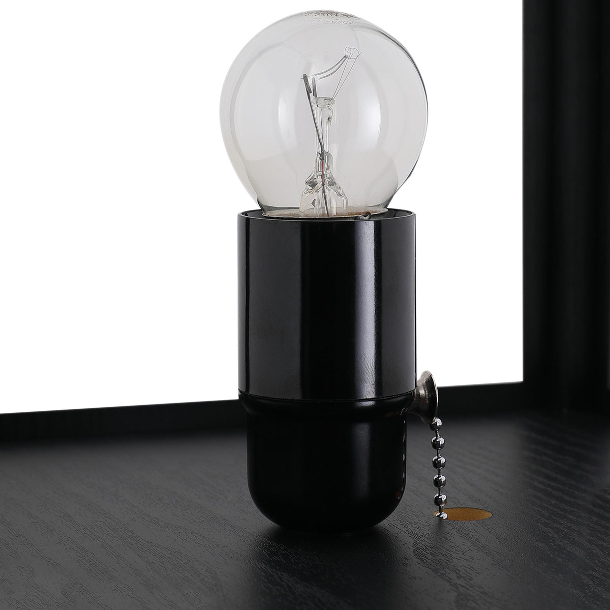 Close-up of the black lamp socket, clear bulb, and pull-chain switch