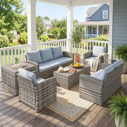 Gray wicker patio furniture set arranged with sectional sofa, armchairs and tables
