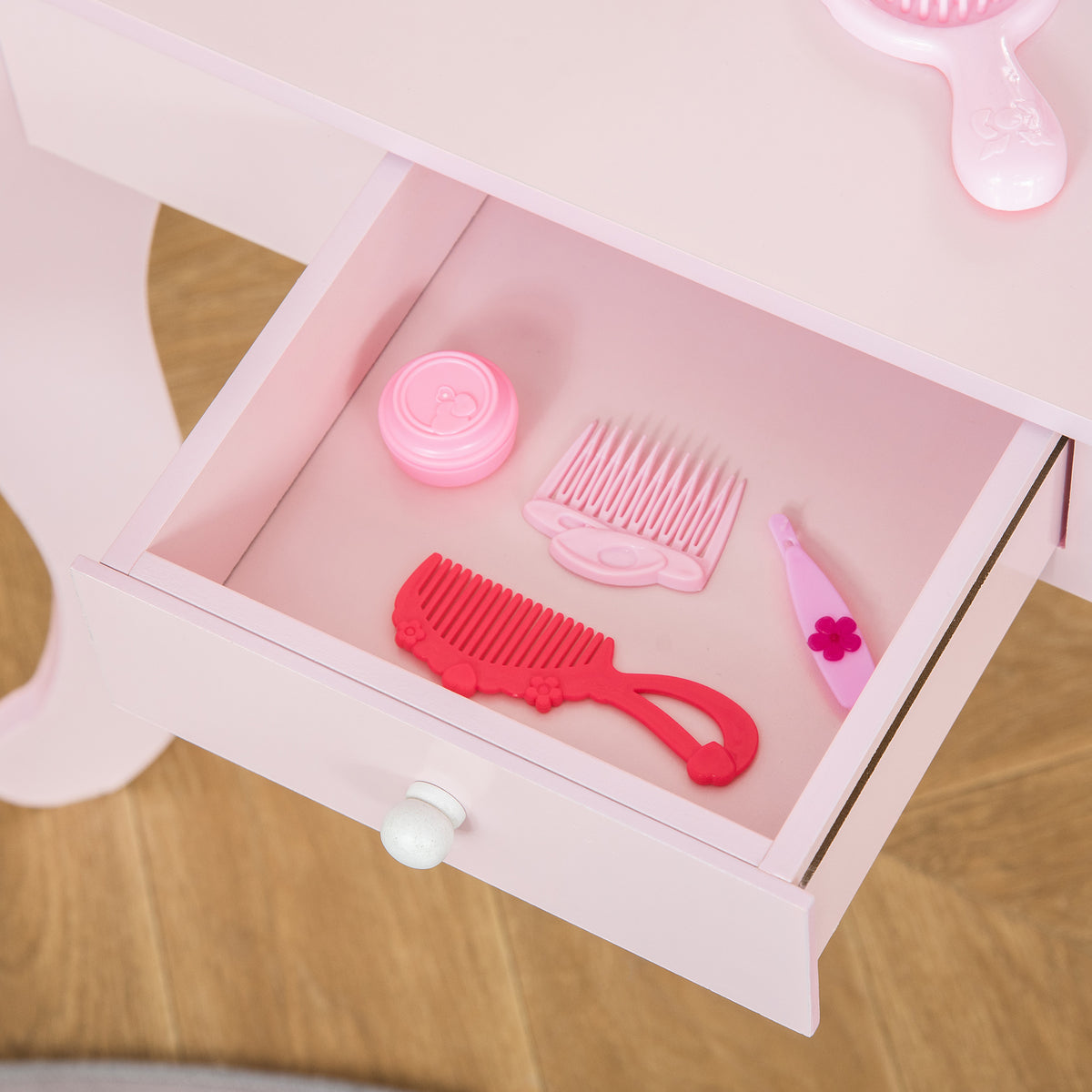 Open pink vanity drawer holding toy combs, brush and hair accessories