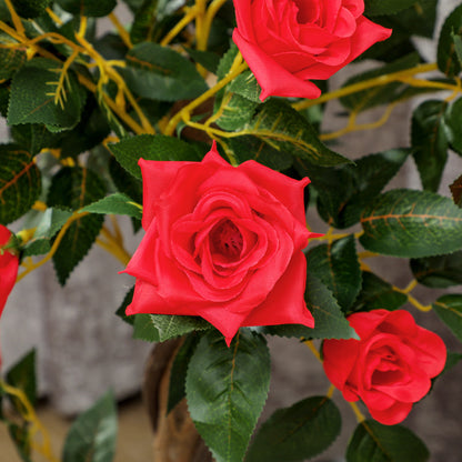 Close-up of artificial red rose blooms and textured green leaves