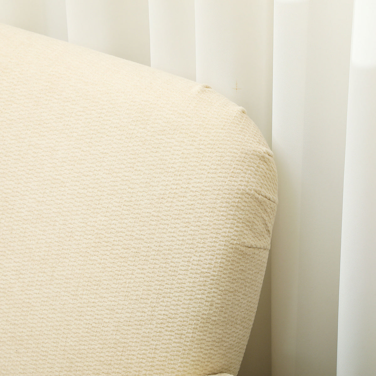 Close-up of the cream loveseat's textured fabric upholstery and rounded back corner