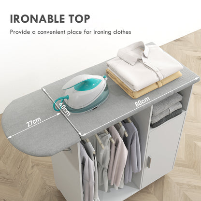 Gray padded ironing board top on a white cabinet with hanging clothes and storage
