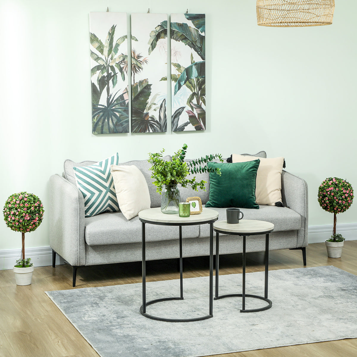 Pair of artificial rose topiary trees in white pots flanking a living room sofa