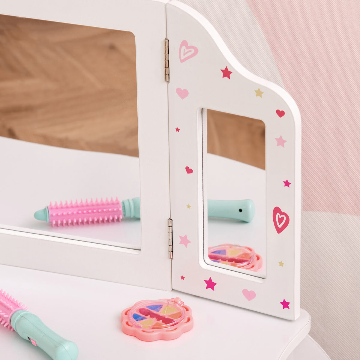 White tri-fold vanity mirror with pink and yellow decals above a tabletop