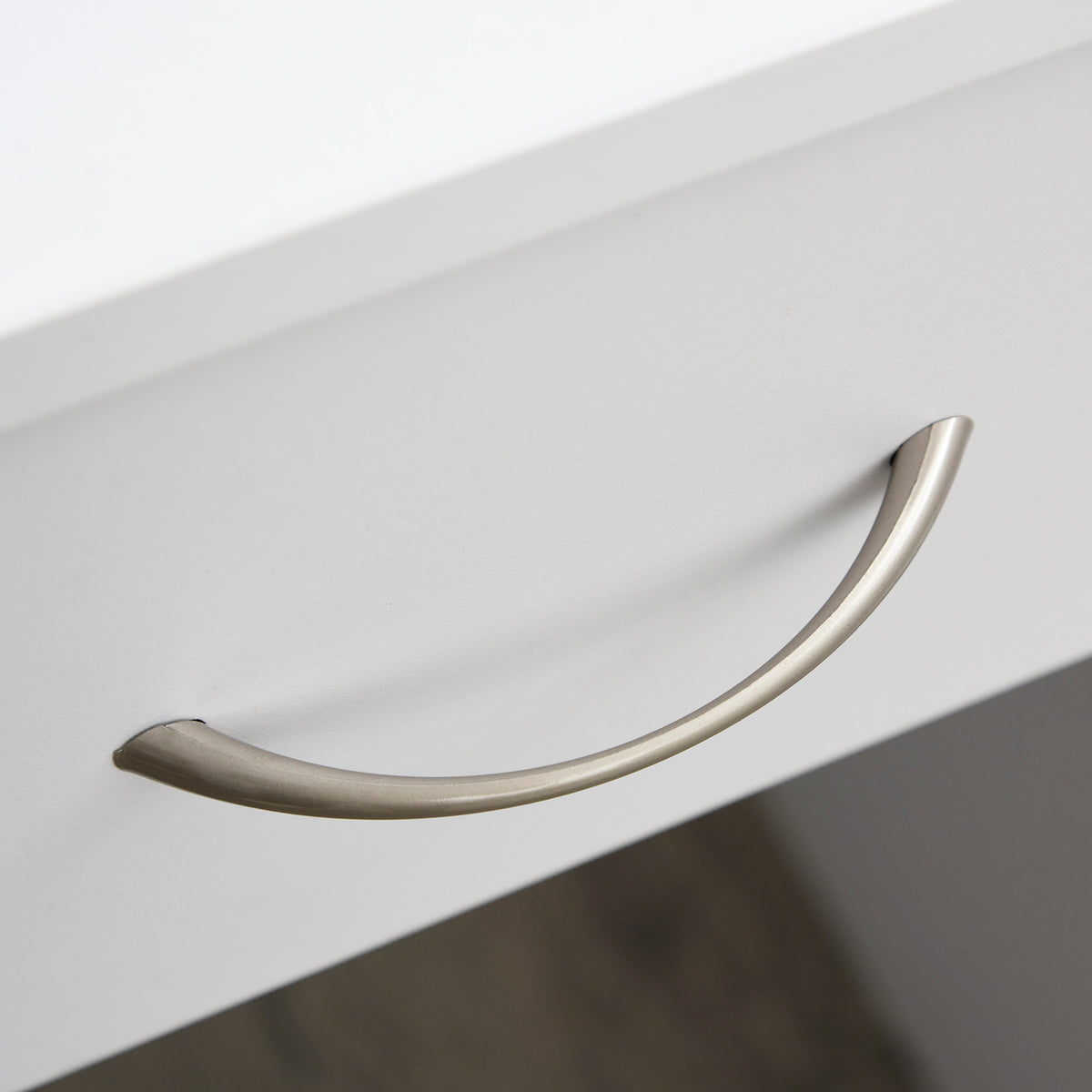 Close-up of the curved metal handle on the desk drawer.