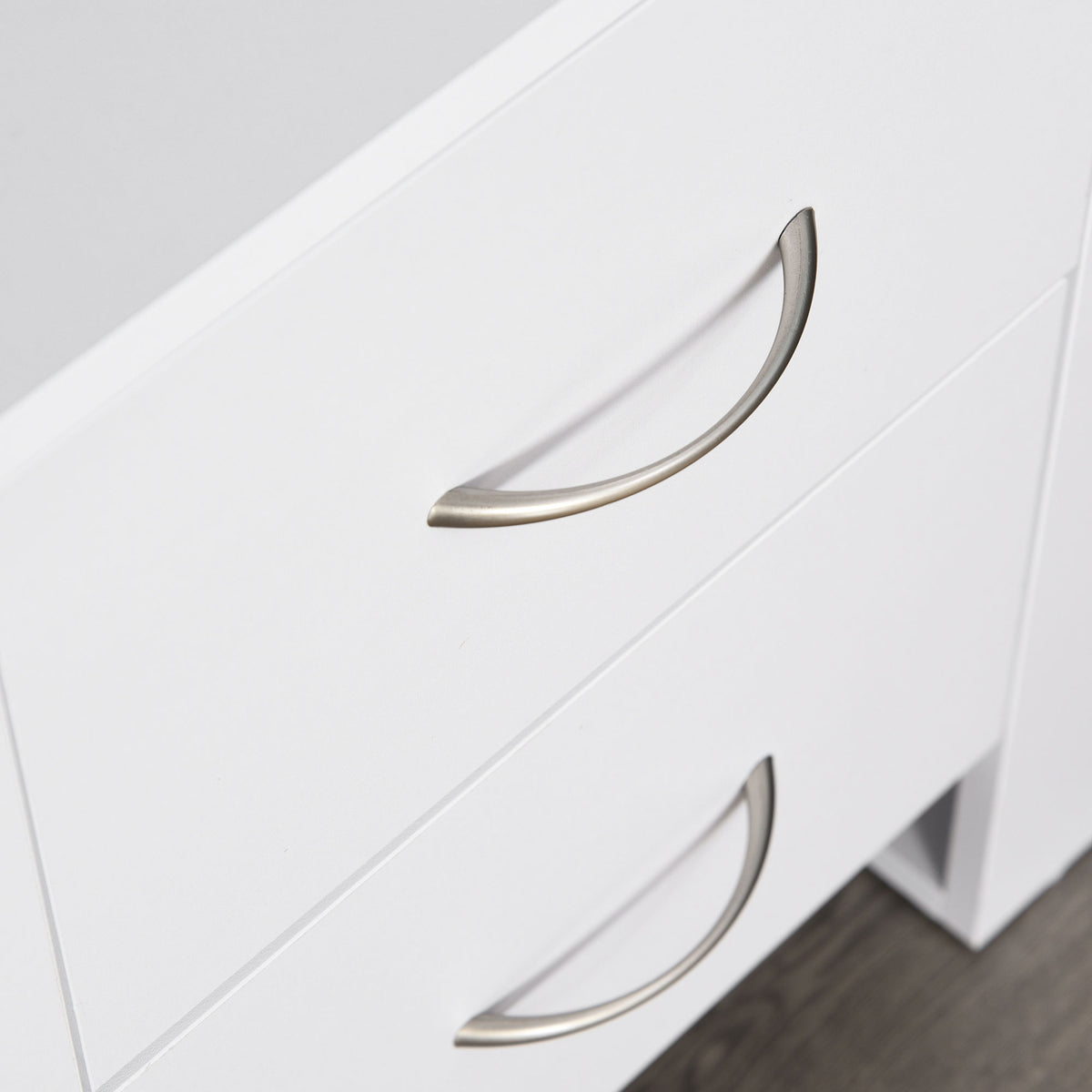 Close-up of two curved metal handles on the white bedside table drawers.