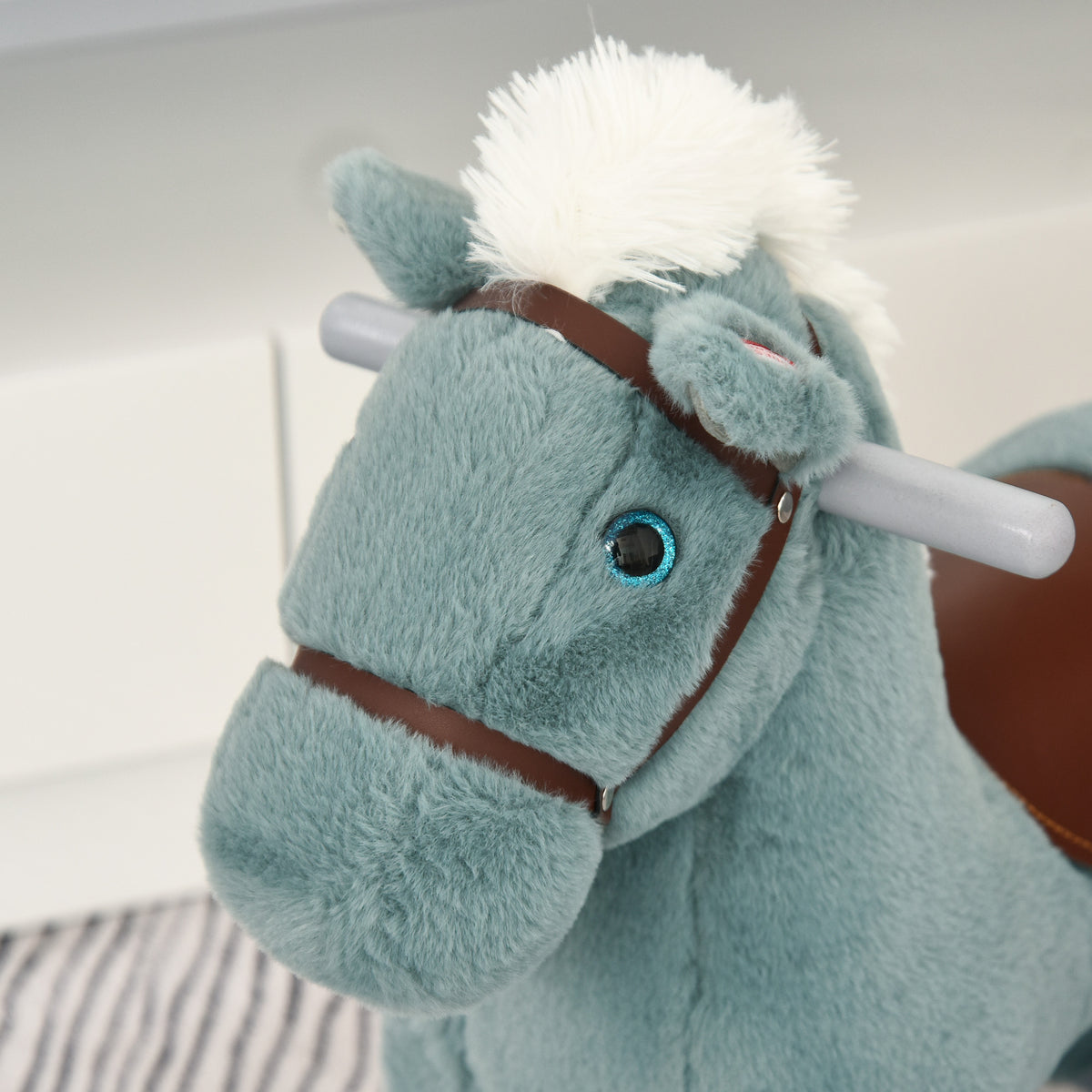 Close-up of blue plush rocking horse head with brown bridle and gray handle